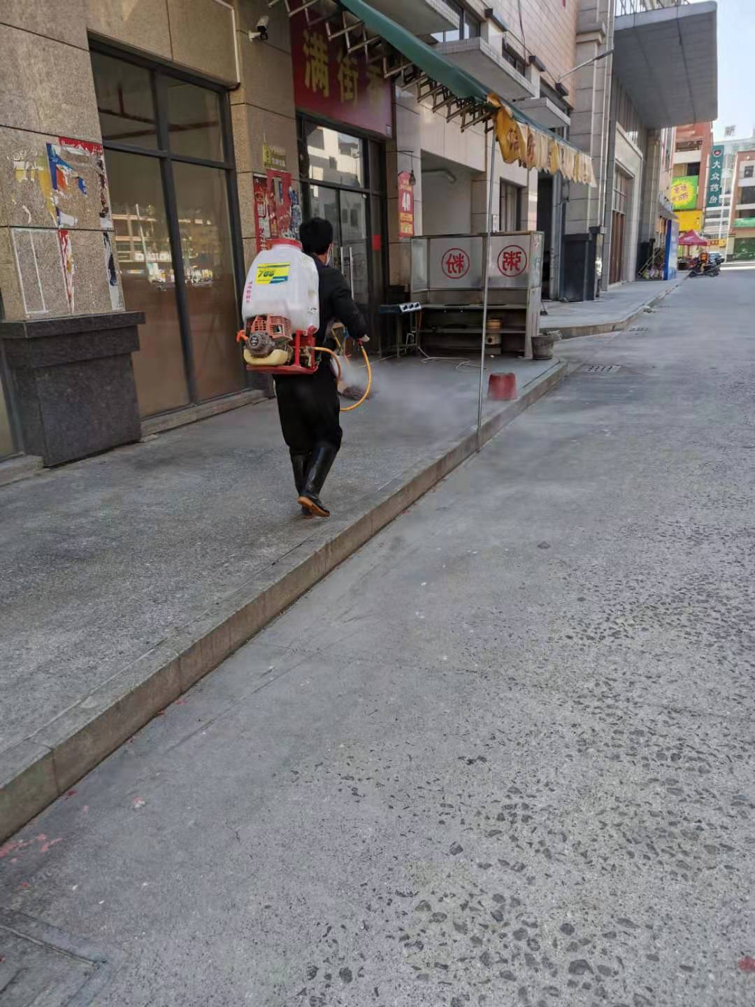 工作人员对店铺前的街道进行消毒